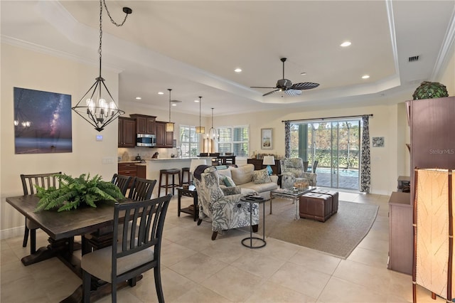 tiled living room with ceiling fan with notable chandelier, crown molding, and a tray ceiling