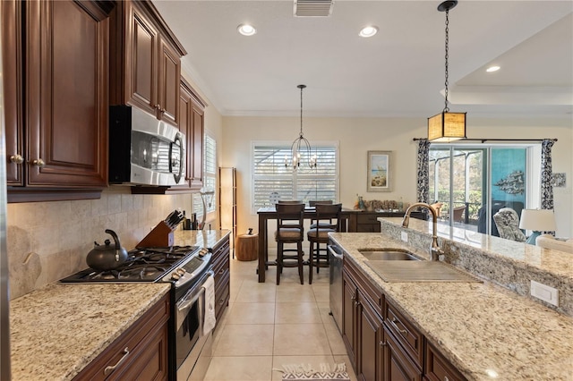 kitchen featuring appliances with stainless steel finishes, backsplash, sink, an inviting chandelier, and hanging light fixtures