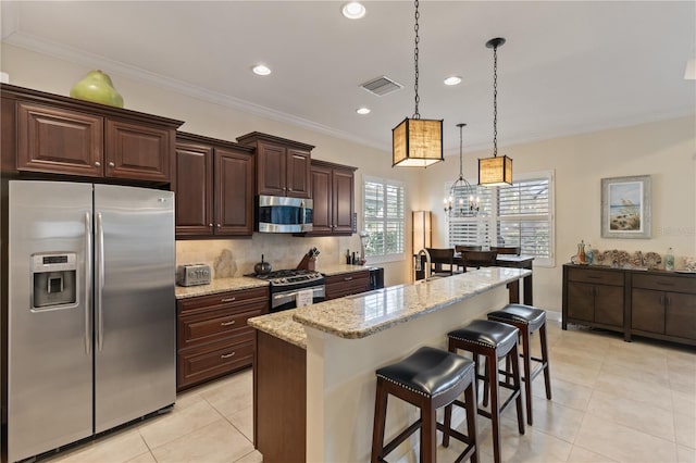 kitchen featuring light stone countertops, stainless steel appliances, a kitchen breakfast bar, crown molding, and an island with sink