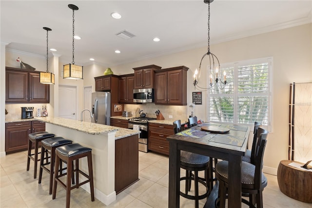 kitchen with a kitchen breakfast bar, ornamental molding, stainless steel appliances, decorative light fixtures, and a chandelier