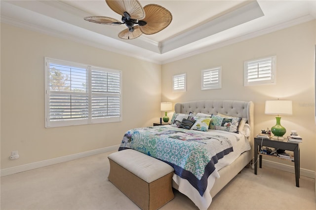 carpeted bedroom with ceiling fan, a raised ceiling, ornamental molding, and multiple windows