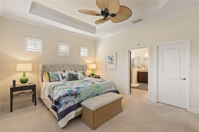 carpeted bedroom featuring a tray ceiling, ensuite bath, ceiling fan, and crown molding