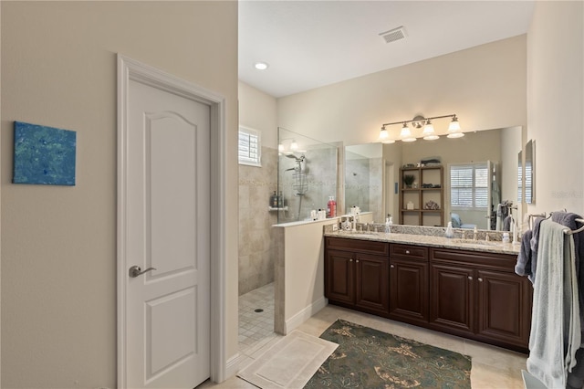 bathroom with tiled shower, vanity, and tile patterned floors