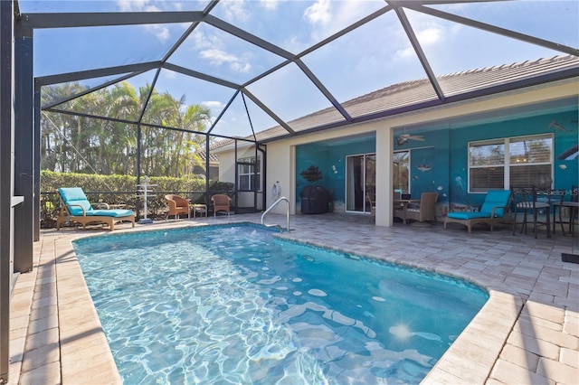 view of pool featuring glass enclosure, ceiling fan, and a patio area