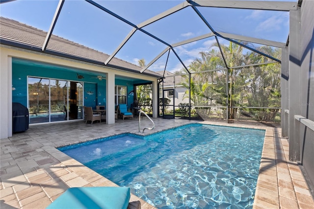 view of swimming pool featuring glass enclosure, ceiling fan, and a patio area