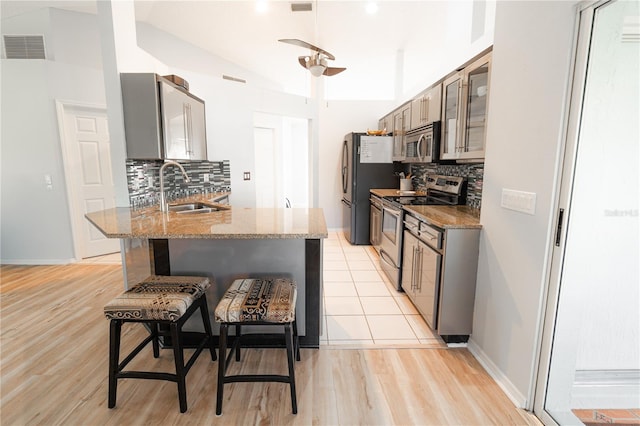 kitchen featuring lofted ceiling, backsplash, a kitchen breakfast bar, sink, and stainless steel appliances