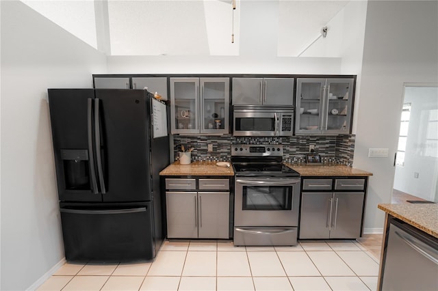 kitchen featuring gray cabinetry, light tile patterned flooring, light stone countertops, and appliances with stainless steel finishes