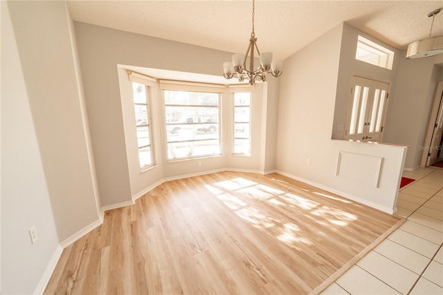 unfurnished dining area with a notable chandelier, light hardwood / wood-style floors, and a textured ceiling