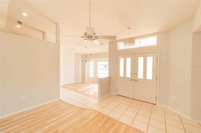 tiled entrance foyer with ceiling fan and a textured ceiling