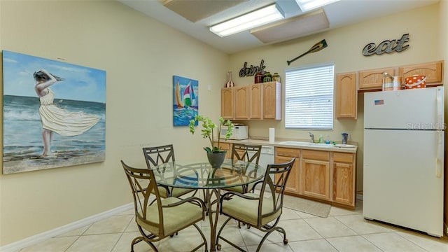 kitchen featuring white fridge, light tile patterned floors, sink, and light brown cabinets