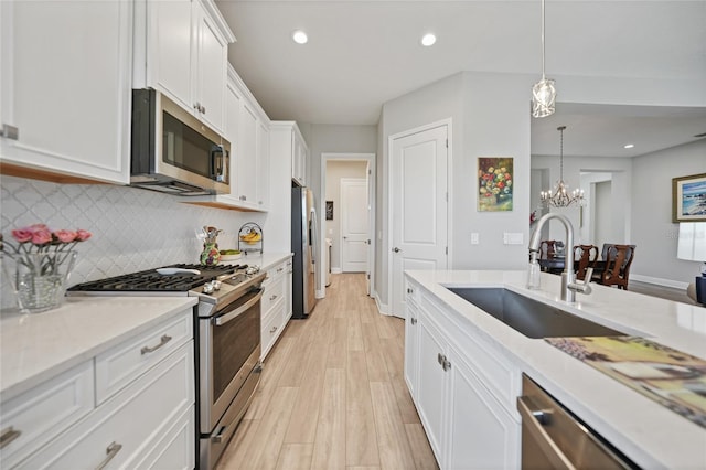 kitchen with sink, stainless steel appliances, light hardwood / wood-style flooring, pendant lighting, and white cabinets