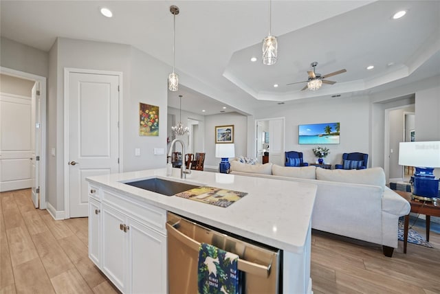 kitchen featuring decorative light fixtures, stainless steel dishwasher, open floor plan, a kitchen island with sink, and white cabinetry