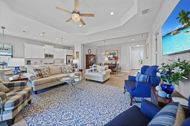 living room featuring recessed lighting, visible vents, a tray ceiling, light wood finished floors, and crown molding