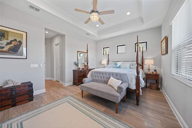 bedroom featuring light wood-style flooring, visible vents, a raised ceiling, and baseboards