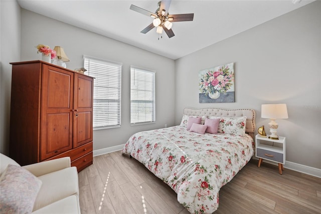 bedroom with a ceiling fan, light wood-style flooring, and baseboards