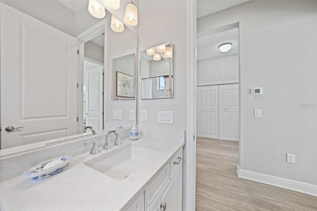 bathroom featuring wood finished floors, vanity, and baseboards