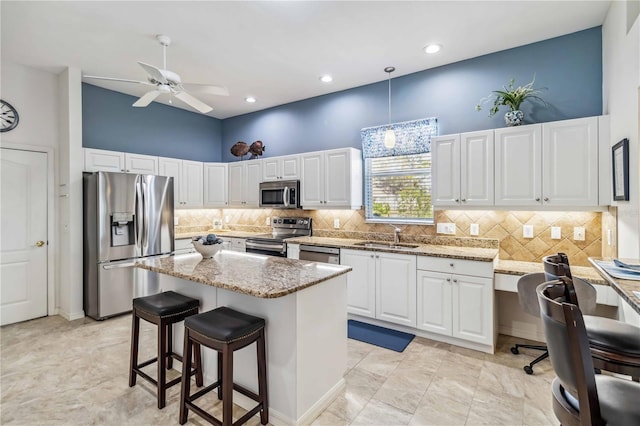 kitchen featuring sink, a center island, hanging light fixtures, stainless steel appliances, and white cabinets