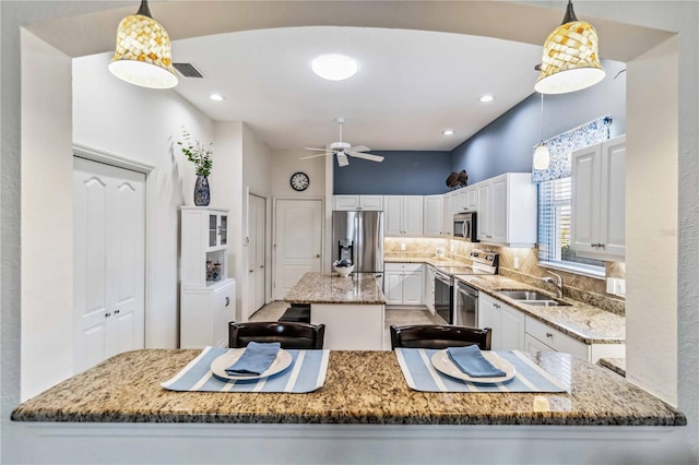 kitchen with white cabinetry, appliances with stainless steel finishes, a center island, and hanging light fixtures