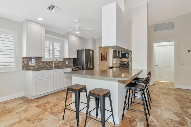 kitchen featuring ceiling fan, kitchen peninsula, a breakfast bar area, white cabinets, and appliances with stainless steel finishes