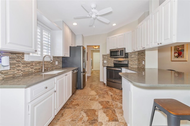 kitchen with white cabinets, a kitchen breakfast bar, sink, appliances with stainless steel finishes, and kitchen peninsula