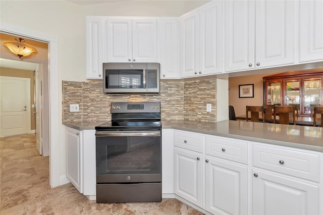 kitchen with backsplash, kitchen peninsula, white cabinets, and stainless steel appliances