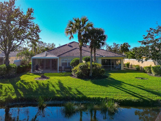 rear view of house featuring a lawn and a sunroom