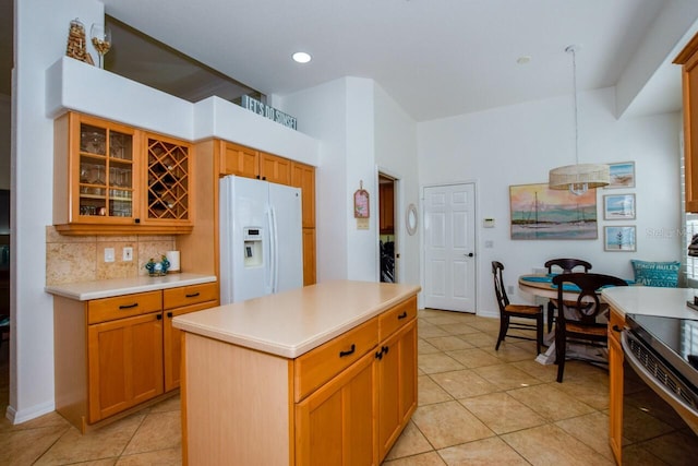 kitchen featuring backsplash, light tile patterned floors, a kitchen island, and white fridge with ice dispenser