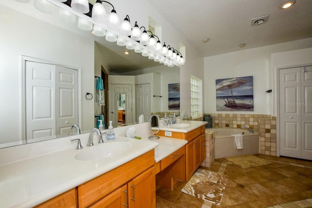 bathroom with tile patterned flooring, vanity, and a relaxing tiled tub