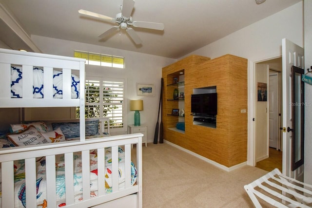 bedroom featuring a nursery area, light colored carpet, and ceiling fan