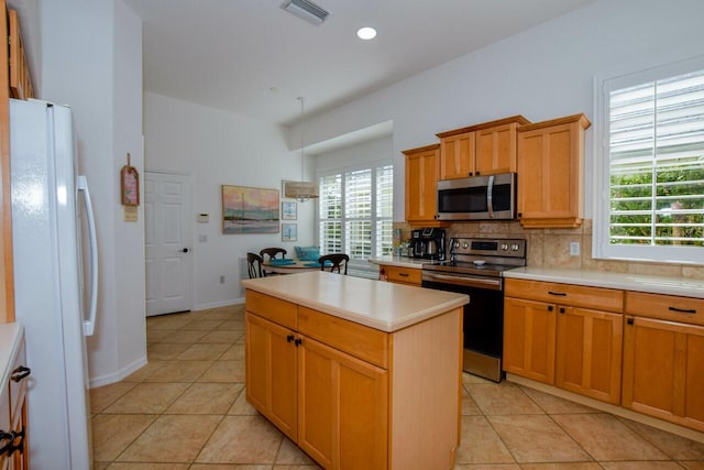 kitchen featuring stainless steel appliances, tasteful backsplash, a center island, and light tile patterned floors