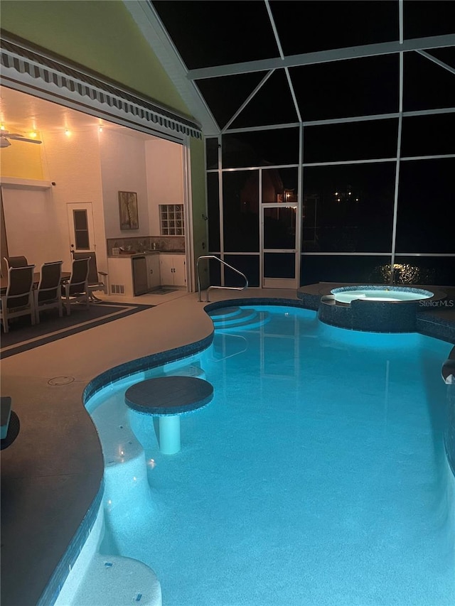 view of swimming pool with an in ground hot tub, an outdoor kitchen, glass enclosure, and a patio area