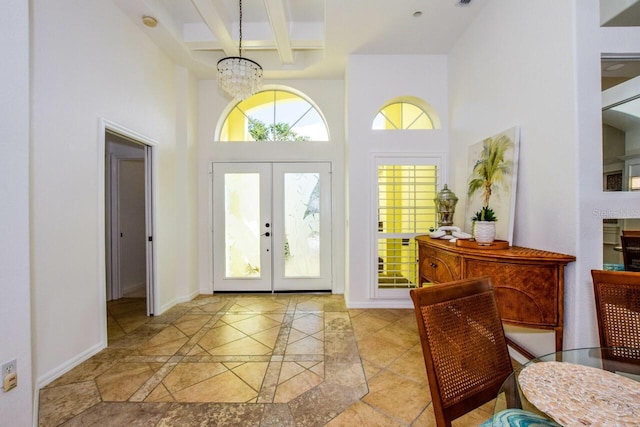 entryway featuring french doors, a towering ceiling, beam ceiling, and a notable chandelier