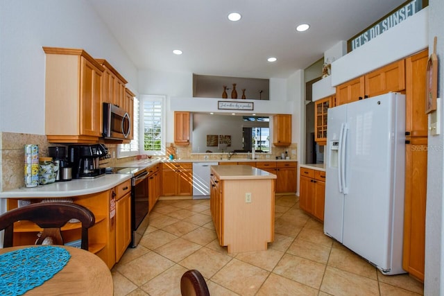 kitchen with appliances with stainless steel finishes, a center island, tasteful backsplash, light tile patterned flooring, and kitchen peninsula