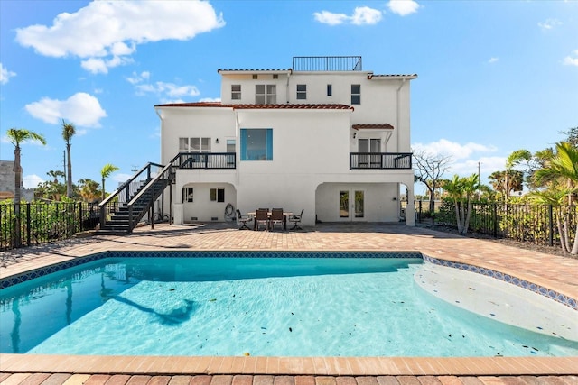 back of property featuring french doors, a patio, a fenced in pool, and a balcony