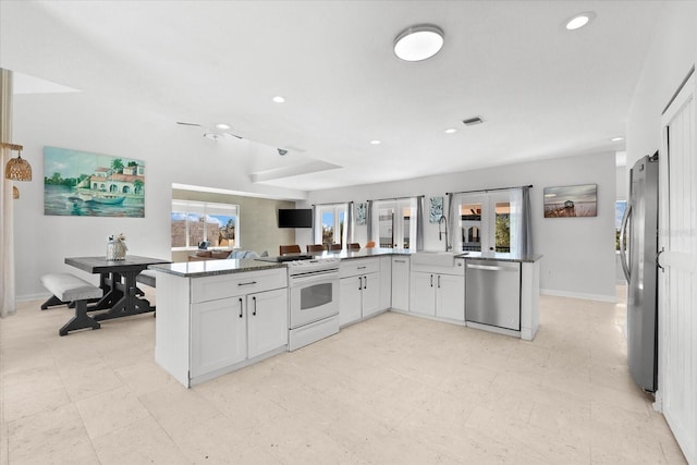 kitchen with white cabinets, kitchen peninsula, stainless steel appliances, and a wealth of natural light