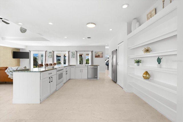 kitchen featuring ceiling fan, dark stone countertops, white cabinetry, kitchen peninsula, and stainless steel appliances