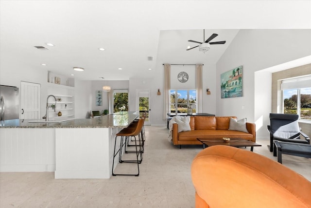 kitchen with stainless steel fridge, a wealth of natural light, light stone countertops, and vaulted ceiling