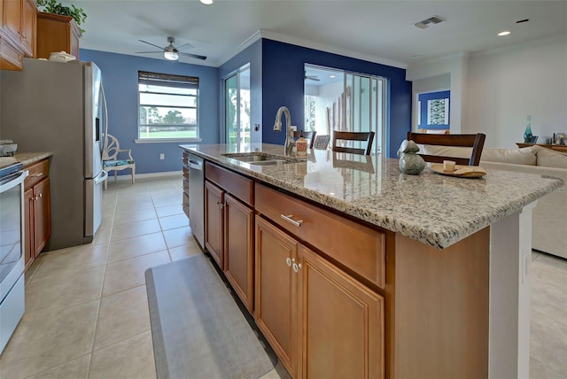 kitchen featuring light stone counters, ceiling fan, sink, a center island with sink, and light tile patterned flooring