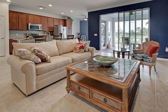 tiled living room with ceiling fan and ornamental molding