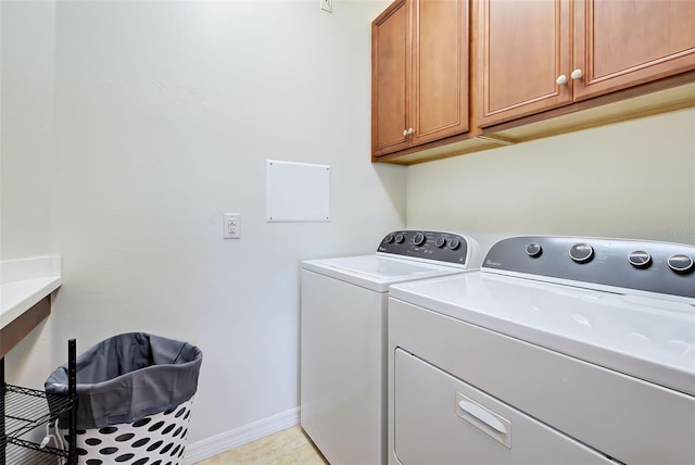 clothes washing area with washer and dryer, light tile patterned flooring, and cabinets