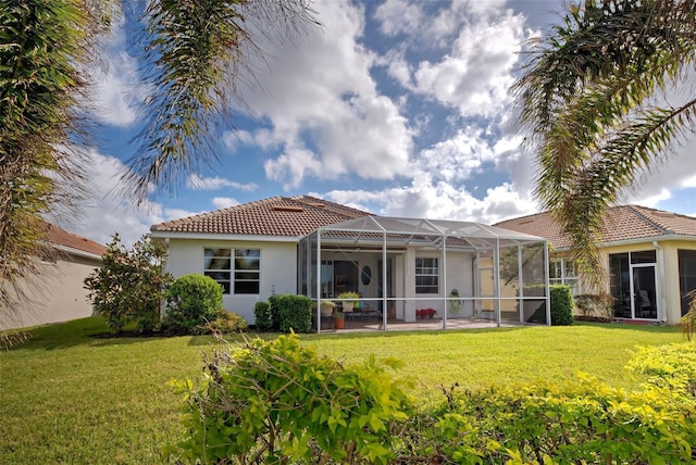 rear view of house featuring glass enclosure, a patio area, and a yard