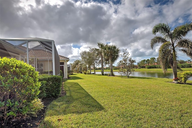 view of yard with a lanai and a water view