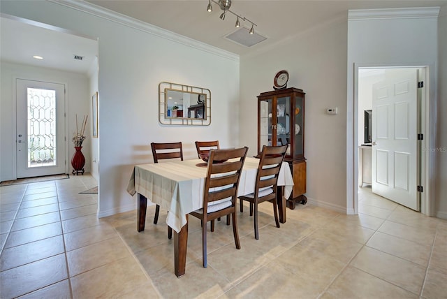 tiled dining room featuring crown molding and track lighting