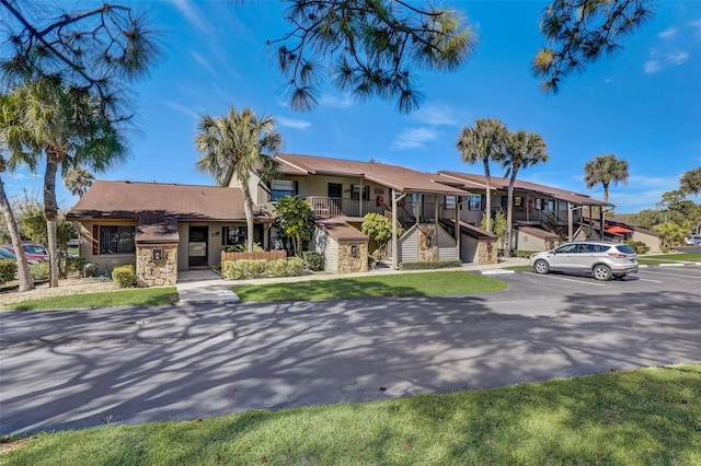 view of front of house featuring a balcony and a front lawn