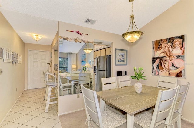 dining space with light tile patterned floors, a textured ceiling, and vaulted ceiling