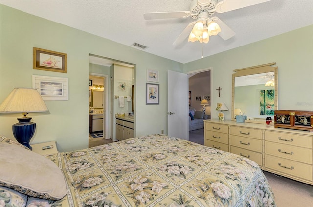 bedroom featuring a textured ceiling, connected bathroom, and ceiling fan