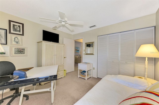 carpeted bedroom with ceiling fan, a textured ceiling, and a closet