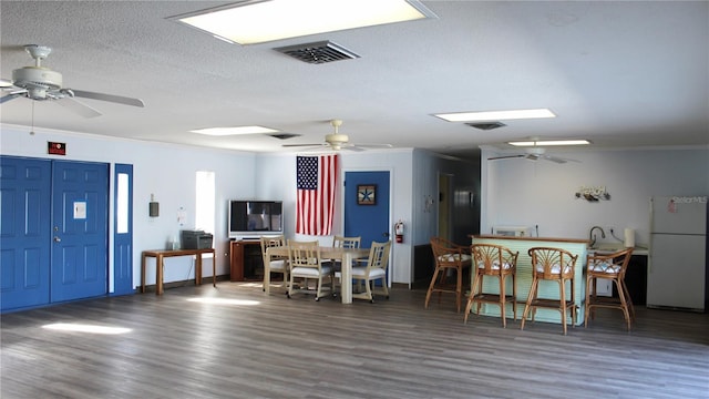 dining space with sink, dark wood-type flooring, a textured ceiling, and ornamental molding