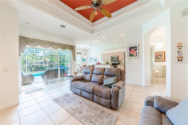 tiled living room featuring crown molding, ceiling fan, and a tray ceiling