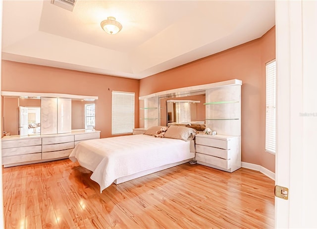 unfurnished bedroom featuring hardwood / wood-style flooring and a raised ceiling